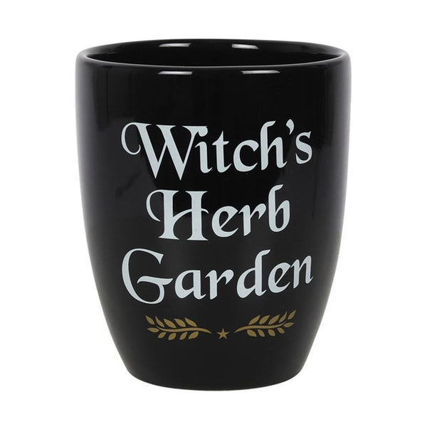 A black ceramic plant pot with the text 'WITCH'S HERB GARDEN' written in white and gold letters, along with a decorative leafy design.