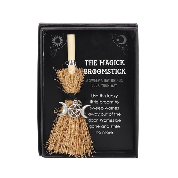 A packaged mini broomstick with a straw handle and a decorative triple moon design on the brush, labeled 'The Magic Broomstick'.